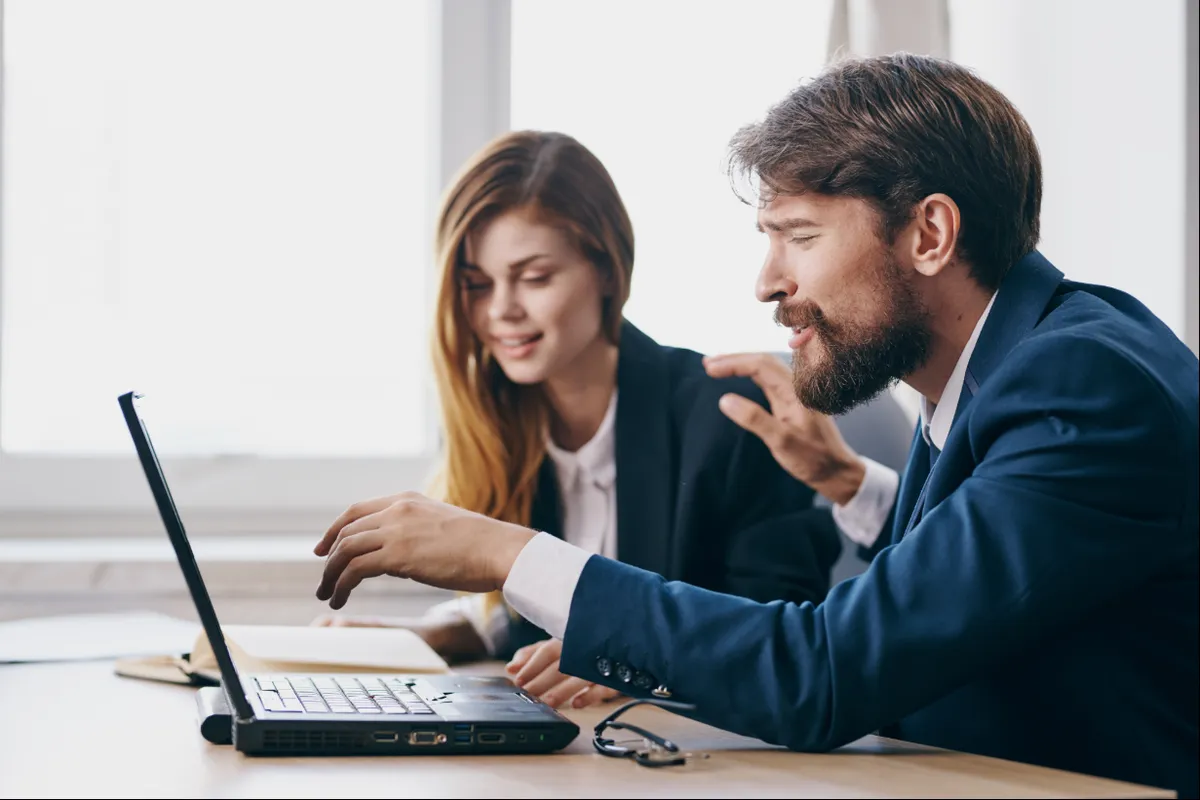 Two professionals reviewing course material on a laptop